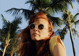 four diverse woman with different hair colors and lenghts, which stand side by side and close to each other looking into the camera while standing in front of a clean grey background